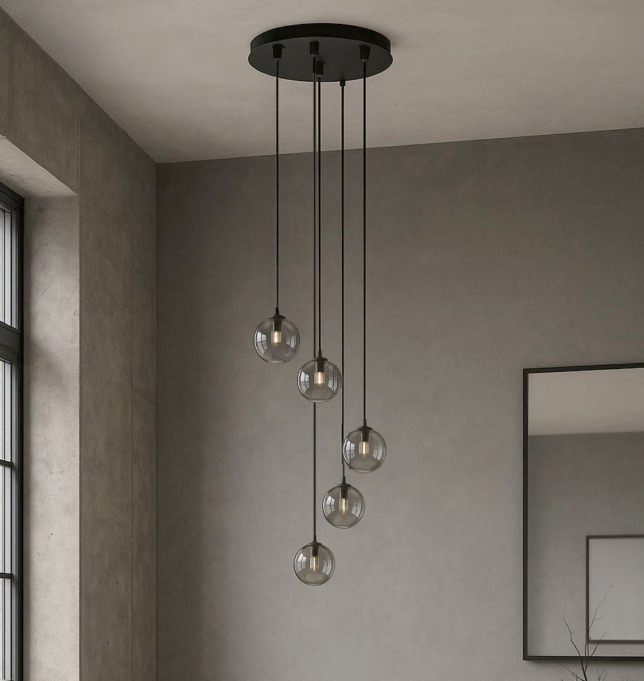 Lampa wisząca Dori, pięć kulistych kloszy w kolorze grafitowym, zawieszonych na cienkich czarnych linkach. Ujęcie z dołu, z widocznym sufitowym mocowaniem. Minimalistyczne tło w odcieniach szarości, z odbiciem w lustrze.