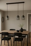 Lampa wisząca Miri 3xE27 w kolorze czarnym i grafitowym, z trzema szklanymi kloszami o prostokątnym kształcie, zawieszona na czarnej listwie. Produkt zainstalowany nad drewnianym stołem w minimalistycznej aranżacji wnętrza.