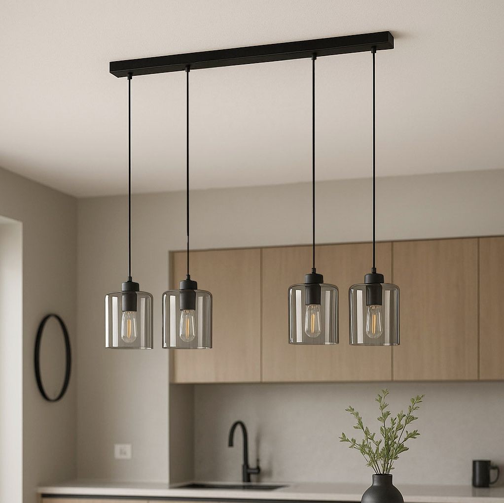 Lampa wisząca Miri z czterema kloszami E27 w kolorze czarnym i grafitowym. Klosze w formie szklanych cylindrów z metalowymi elementami, zawieszone na cienkich linkach. Produkt umieszczony nad blatem w nowoczesnej kuchni z drewnianymi szafkami w tle.