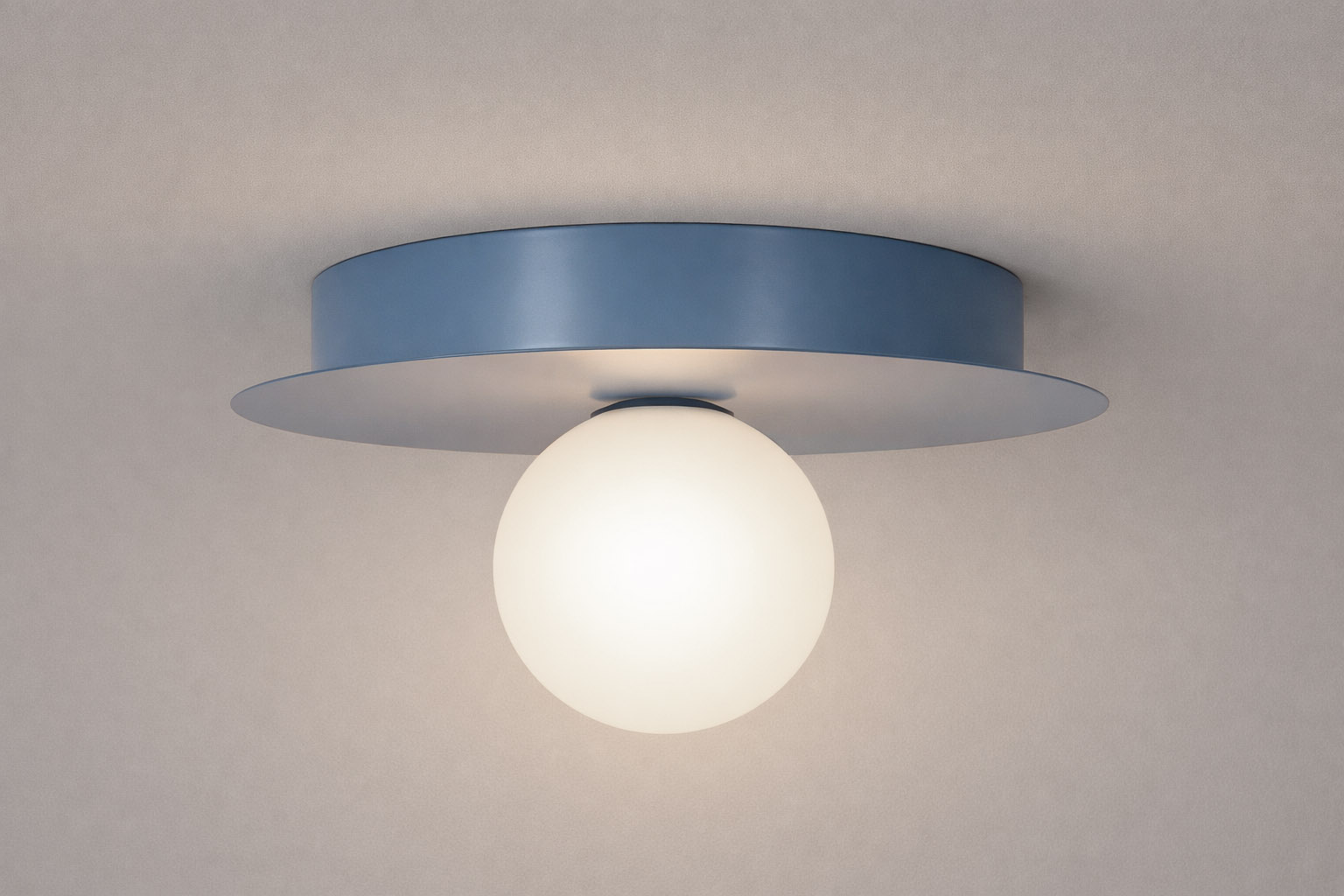 Lampa sufitowa Robin D25 w kolorze niebieskim i białym, z okrągłym kloszem z mlecznego szkła, zamontowana na płaskim, niebieskim stelażu. Ujęcie frontalne, pokazujące detal konstrukcji i kształt.