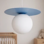 Lampa wisząca Robin D18 w kolorze niebieskim i białym, z okrągłym, matowym kloszem i płaską, błękitną osłoną. Zawieszona na cienkim, przezroczystym przewodzie, idealna do nowoczesnych wnętrz. W tle widoczny pokój dziecięcy z łóżeczkiem.