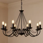 Czarny żyrandol Bartez 8-punktowy, z metalowymi ramionami w formie fal, zamontowany na łańcuchu. Osiem źródeł światła w szklanych kloszach, umieszczonych na podstawach. Tło jasne, jednolite.