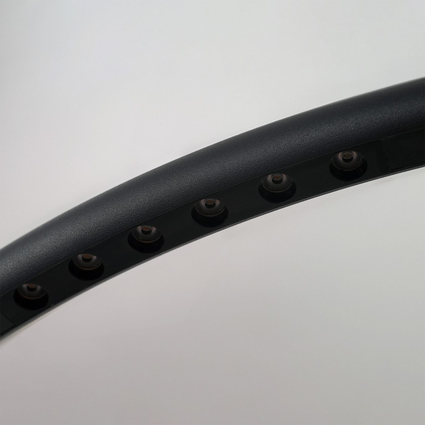 Lampa wisząca Apus w kolorze czarnym z 10 diodami LED. Zbliżenie na okrągły kształt klosza z widocznymi otworami na źródła światła. Powierzchnia matowa, elegancka, z subtelnym połyskiem. Tło jasne, co podkreśla detale lampy.