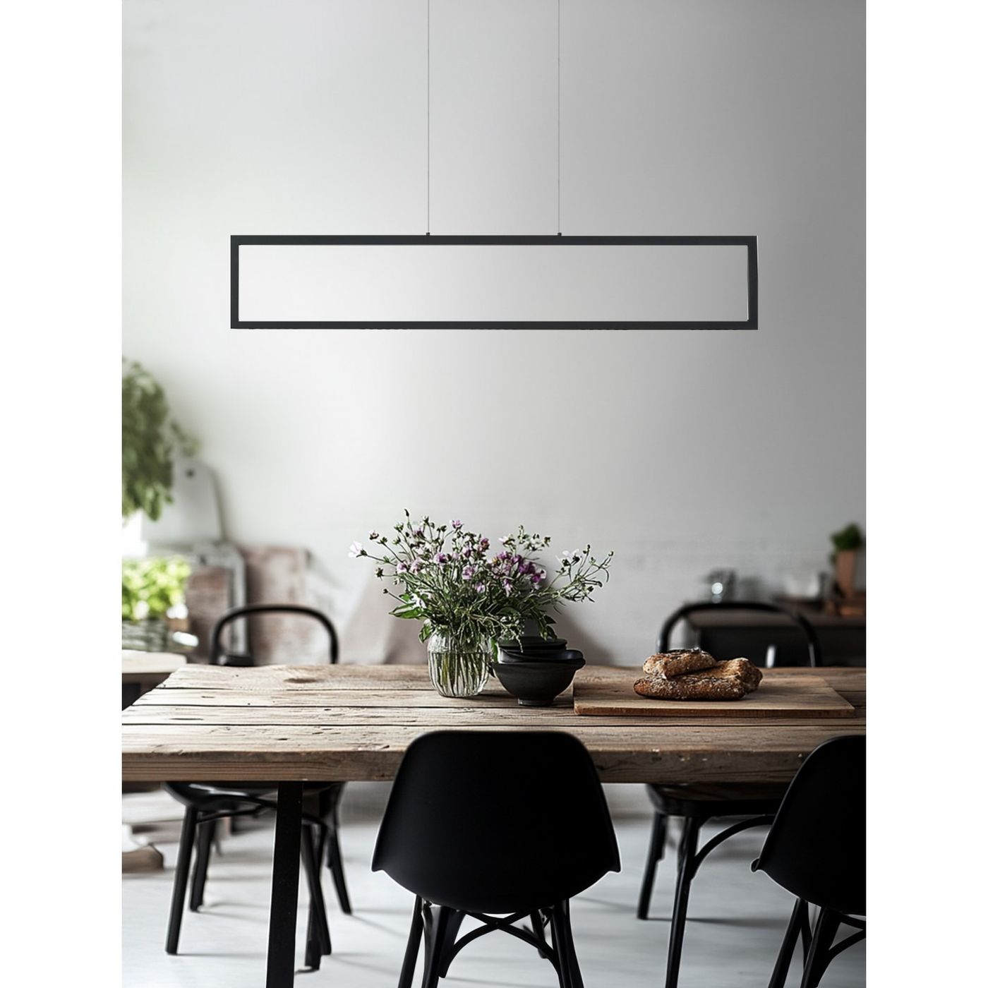 Lampa wisząca LED Fada 34W w kolorze czarnym, o prostokątnym kształcie, zawieszona nad drewnianym stołem. W tle widać bukiet kwiatów w szklanym wazonie oraz czarne krzesła. Tło jasne, minimalistyczne.