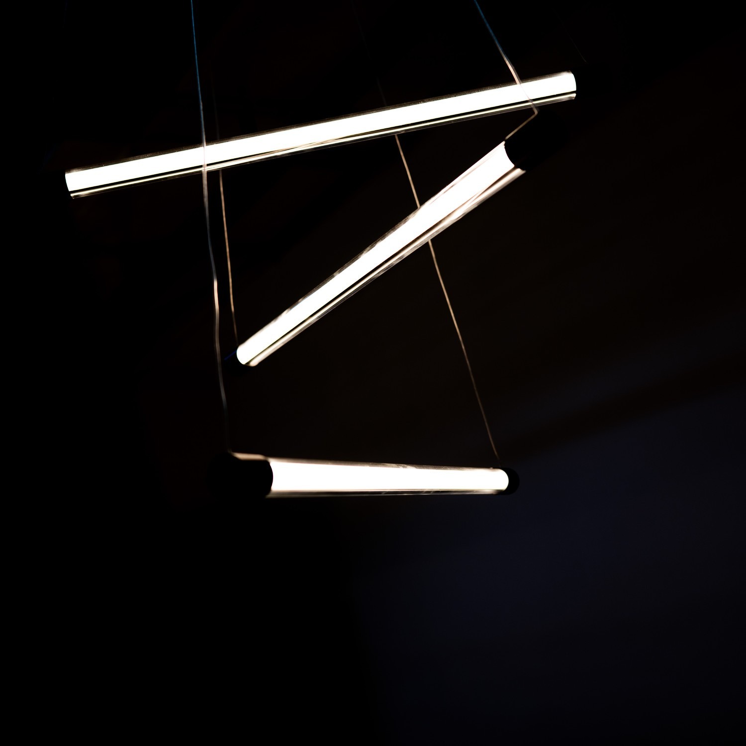 Lampa wisząca Palos 3xLED 29W w kolorze czarnym. Składa się z trzech równoległych, prostokątnych elementów LED, zawieszonych na cienkich linkach. Ujęcie z góry, na ciemnym tle, ukazuje nowoczesny design i źródła światła.