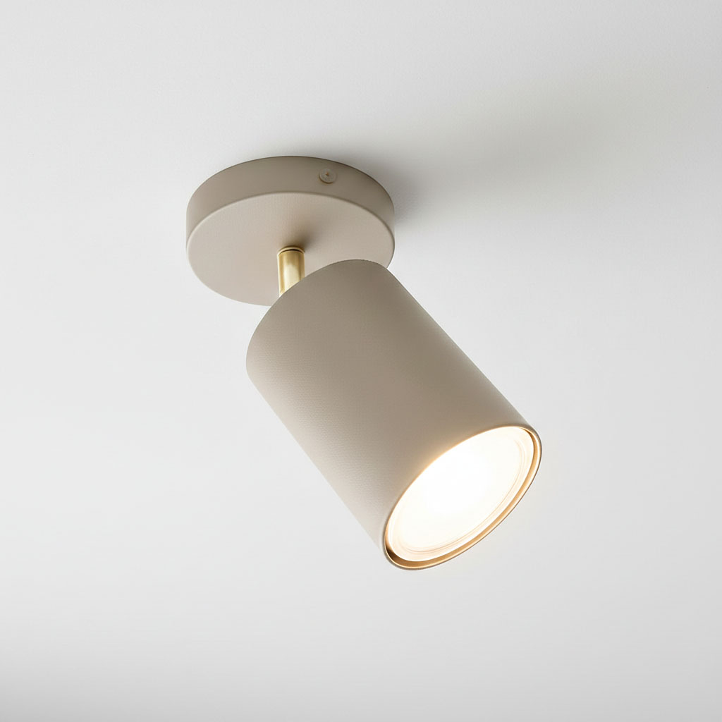 Lampa sufitowa Spoti w odcieniu kaszmiru z metalowym złotym wykończeniem. Cylindryczny klosz z widocznym źródłem światła, zamontowany na okrągłej podstawie. Ujęcie z góry, pokazujące detale i kształt lampy.