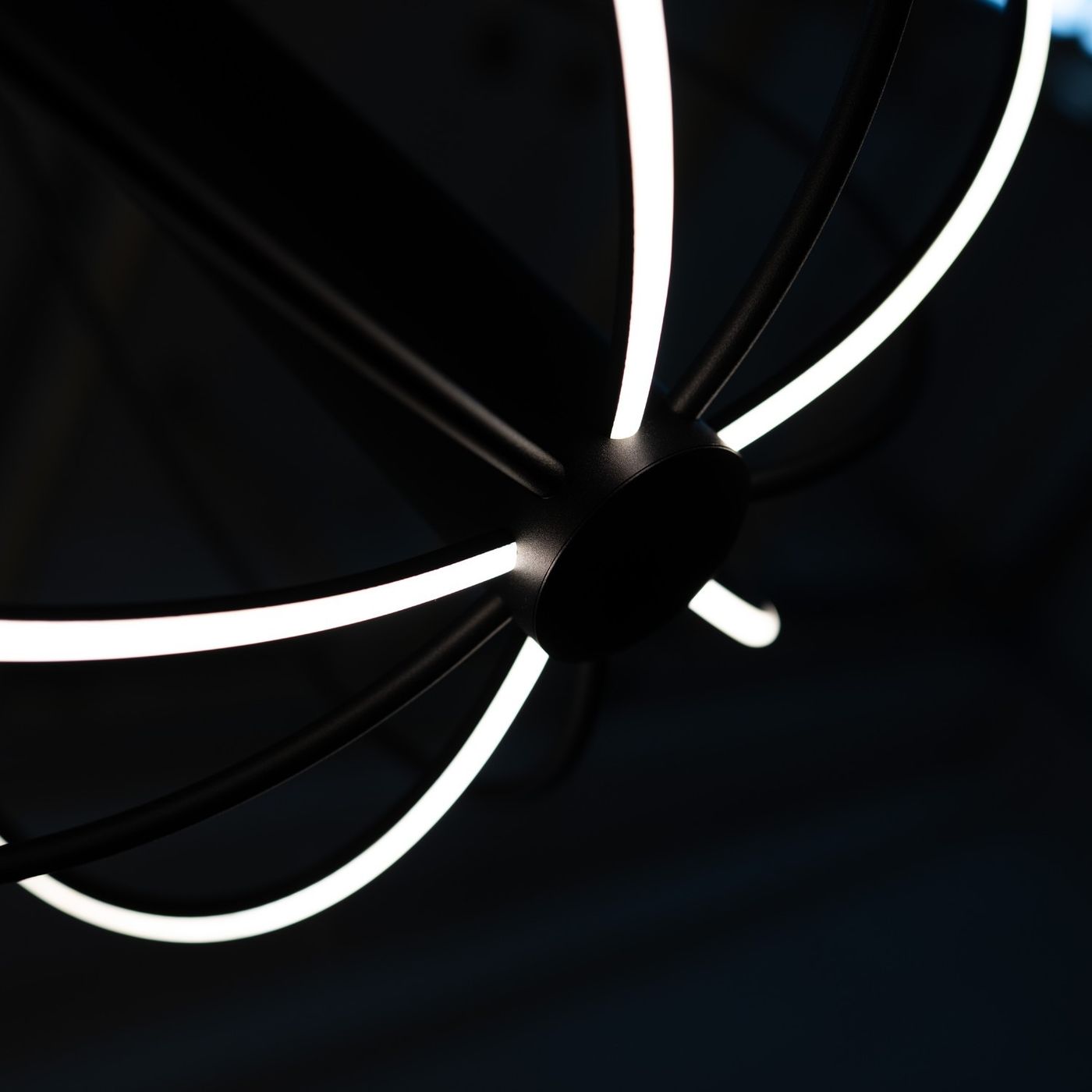 Czarna lampa wisząca LED Zoe 41W z okrągłym, centralnym mocowaniem. Z widocznymi, jasnymi liniami światła w kształcie promieni, które tworzą nowoczesny, minimalistyczny design. Ujęcie z góry, ukazujące detal konstrukcji.