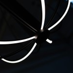 Czarna lampa wisząca LED Zoe 41W z okrągłym, centralnym mocowaniem. Z widocznymi, jasnymi liniami światła w kształcie promieni, które tworzą nowoczesny, minimalistyczny design. Ujęcie z góry, ukazujące detal konstrukcji.