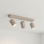 Lampa sufitowa Spoti z trzema spotami GU10 w kolorze kaszmiru z metalowymi złotymi detalami. Ułożona poziomo, z oprawami skierowanymi w dół, na jasnym tle. Idealna do nowoczesnych wnętrz.