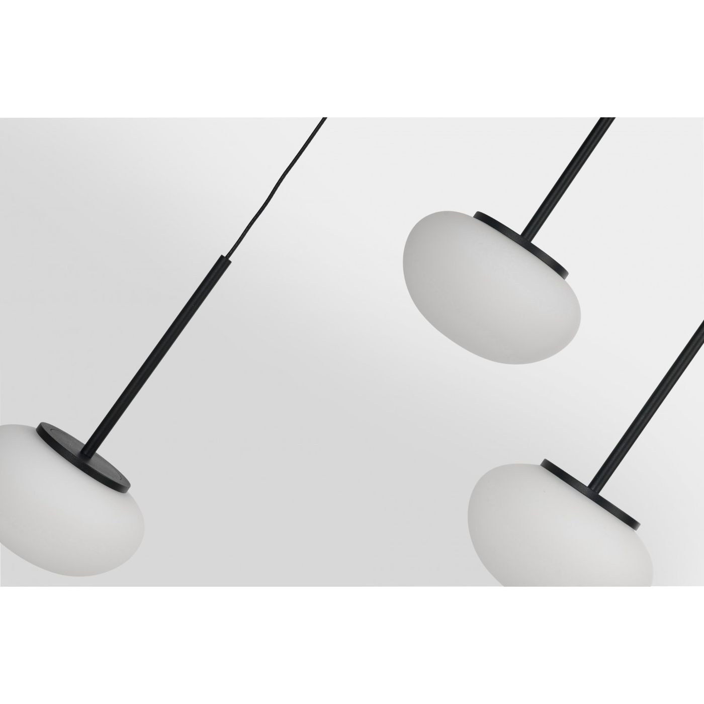 Czarna lampa wisząca Serenity z 12 źródłami LED, o mocy 84W. Ujęcie z góry, ukazujące trzy białe klosze w kształcie kulisty, zawieszone na cienkich czarnych linkach. Tło jasne, minimalistyczne, podkreślające elegancki design lampy.