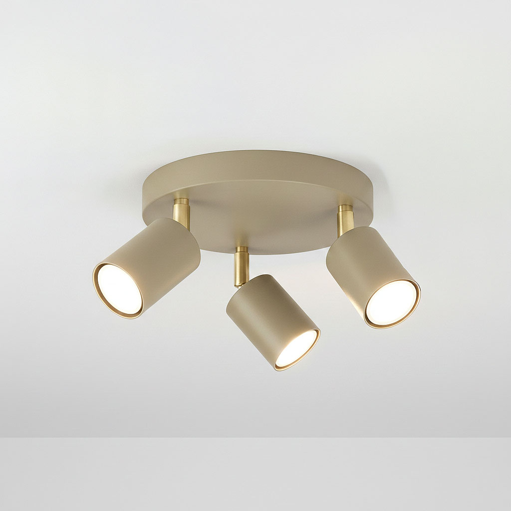 Lampa sufitowa Spoti Round w kolorze kaszmiru z trzema ruchomymi reflektorami. Metalowa konstrukcja z złotymi detalami, montowana na suficie. Reflektory skierowane w różnych kierunkach, zapewniające oświetlenie w pomieszczeniu.