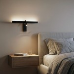Czarny kinkiet Rico z podwójnym źródłem światła LED 16W, zamontowany na ścianie obok łóżka. Posiada minimalistyczny design z jednym ruchomym ramieniem. W tle widoczna nocna szafka z książką i szklanką.