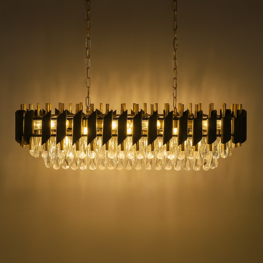 Lampa wisząca Cristal w złotym kolorze, z miejscem na 10 żarówek E14. Posiada dekoracyjne elementy z przezroczystego szkła, wisząca na łańcuchu, układ poziomy, z wyraźnym podziałem na części i teksturą. Tło w odcieniu ciepłego beżu.