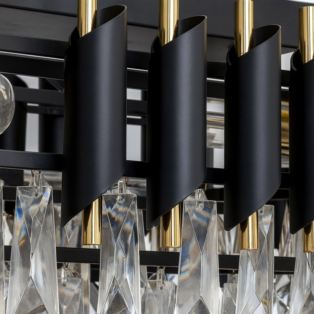 Lampa wisząca Cristal w złotym wykończeniu, z dziewięcioma miejscami na żarówki E14. Widoczne czarne detale w kształcie spirali oraz kryształowe zwisy w formie diamentów, dodające elegancji. Ujęcie z góry z bliska, podkreślające detale.