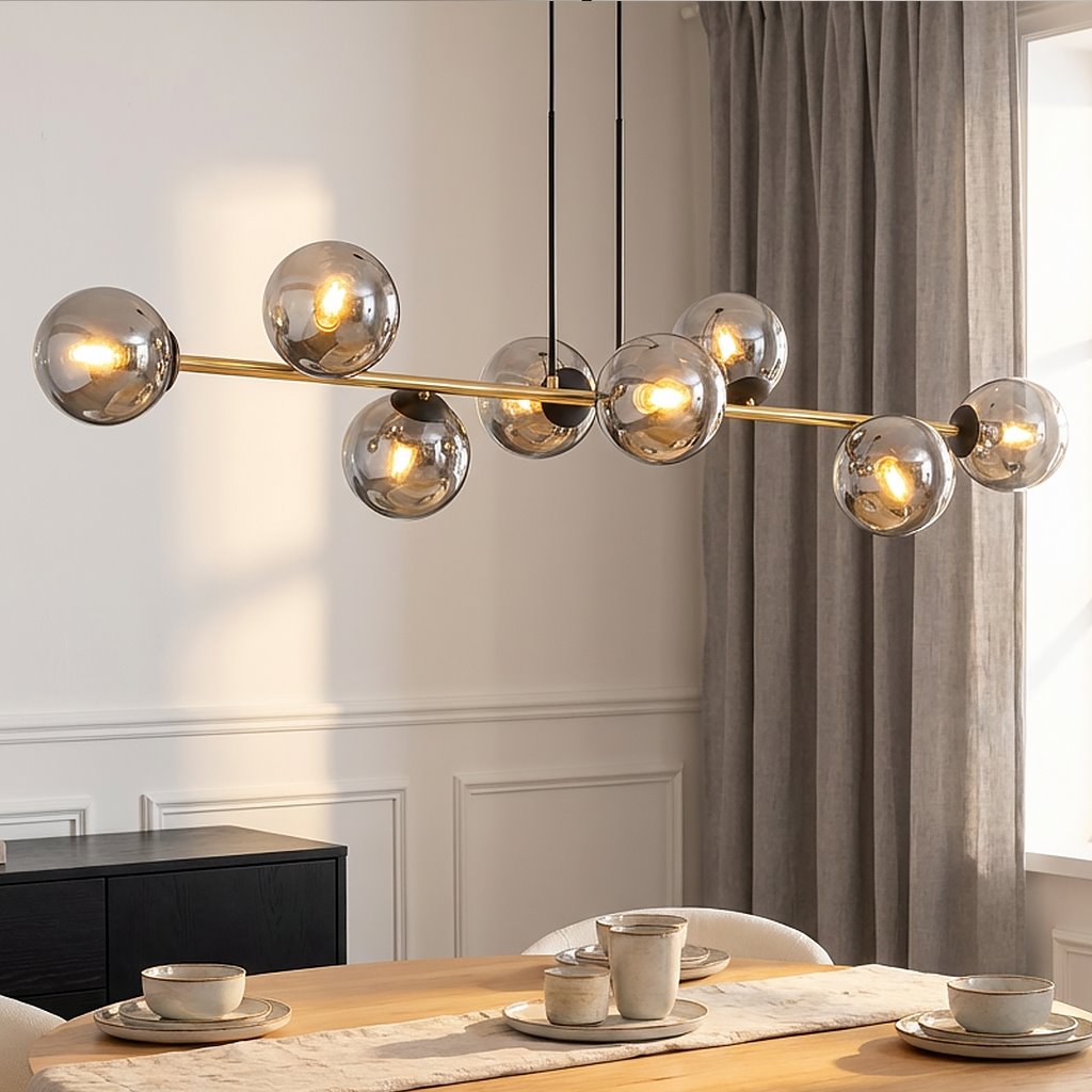 Lampa wisząca Gravity 8-punktowa, czarna z elementami złotymi i grafitowymi. Ośmioelementowa konstrukcja z przezroczystymi kloszami, zawieszona nad stołem jadalnym. Tło jasne, z zasłonami w odcieniu szarości.