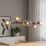 Lampa wisząca Rossi 6-punktowa w kolorze czarnym i grafitowym, z sześcioma przezroczystymi kulistymi kloszami, zawieszona na cienkich linkach. W tle widoczna roślinność oraz minimalistyczne meble w jasnym wnętrzu.