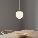 Lampa wisząca Royal 1-punktowa w białym szkle z złotym mocowaniem. Okrągły klosz zwisający z cienkiego kabla, umieszczony nad drewnianym stołem z ceramiczną misą. Tło w odcieniach szarości.