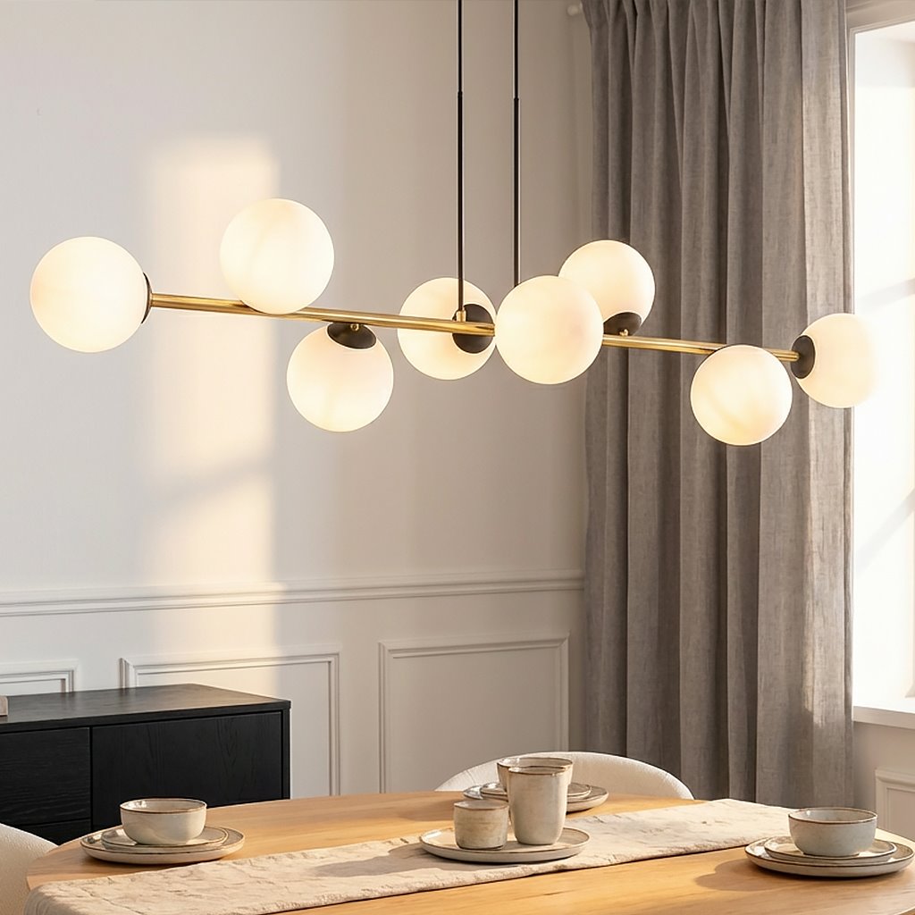 Lampa wisząca Gravity 8-punktowa, czarna i złota, z opalowymi kulistymi kloszami. Ujęcie z góry, zawieszona nad drewnianym stołem, w otoczeniu zastawy stołowej. Prosta, elegancka forma z metalowym stelażem i matowymi kloszami.