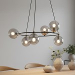 Lampa wisząca Azura z sześcioma oprawami E14, w kolorze czarnym i grafitowym. Okrągła konstrukcja z przezroczystymi kulami, zawieszona na długich linkach. Widoczna w nowoczesnym wnętrzu, na tle drewnianego stołu i ceramicznych wazonów.