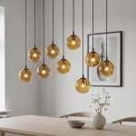 Lampa wisząca Cosmo 9-punktowa w kolorze miodowym, składająca się z dziewięciu szklanych kul zawieszonych na czarnych przewodach. Kule emitują ciepłe światło, a całość prezentuje się nowocześnie w jasnym wnętrzu z drewnianym stołem i dekoracją w wazonie.