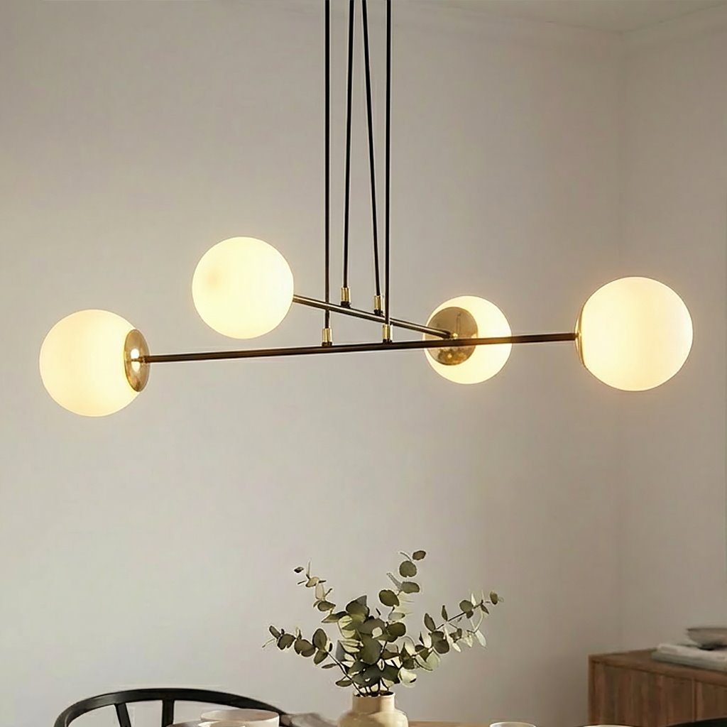 Lampa wisząca Ognis 4-punktowa w czarnej oprawie z czterema białymi, szklanymi kloszami. Ujęcie z boku, zawieszona na cienkich linkach. W tle widoczna aranżacja z roślinnością na stole.