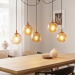 Lampa wisząca Gigi 5-punktowa w kolorze miodowym, składająca się z pięciu szklanych kul z ciepłym światłem, zawieszona na czarnych przewodach. Widoczna w nowoczesnej aranżacji nad drewnianym stołem.