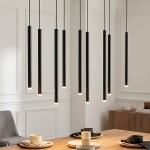 Lampa wisząca Selter 9-punktowa w kolorze czarnym, składająca się z dziewięciu długich, cylindrycznych elementów. Zawieszona na cienkich przewodach, emitująca światło z dolnej krawędzi, w nowoczesnym wnętrzu, nad drewnianym stołem.