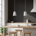 Lampa wisząca Bolero 1-punktowa w białym kolorze, z ceramicznym kloszem o stożkowym kształcie i drewnianym wykończeniem. Zawieszona nad drewnianym stołem w nowoczesnej kuchni, na tle szarej ceglanej ściany.