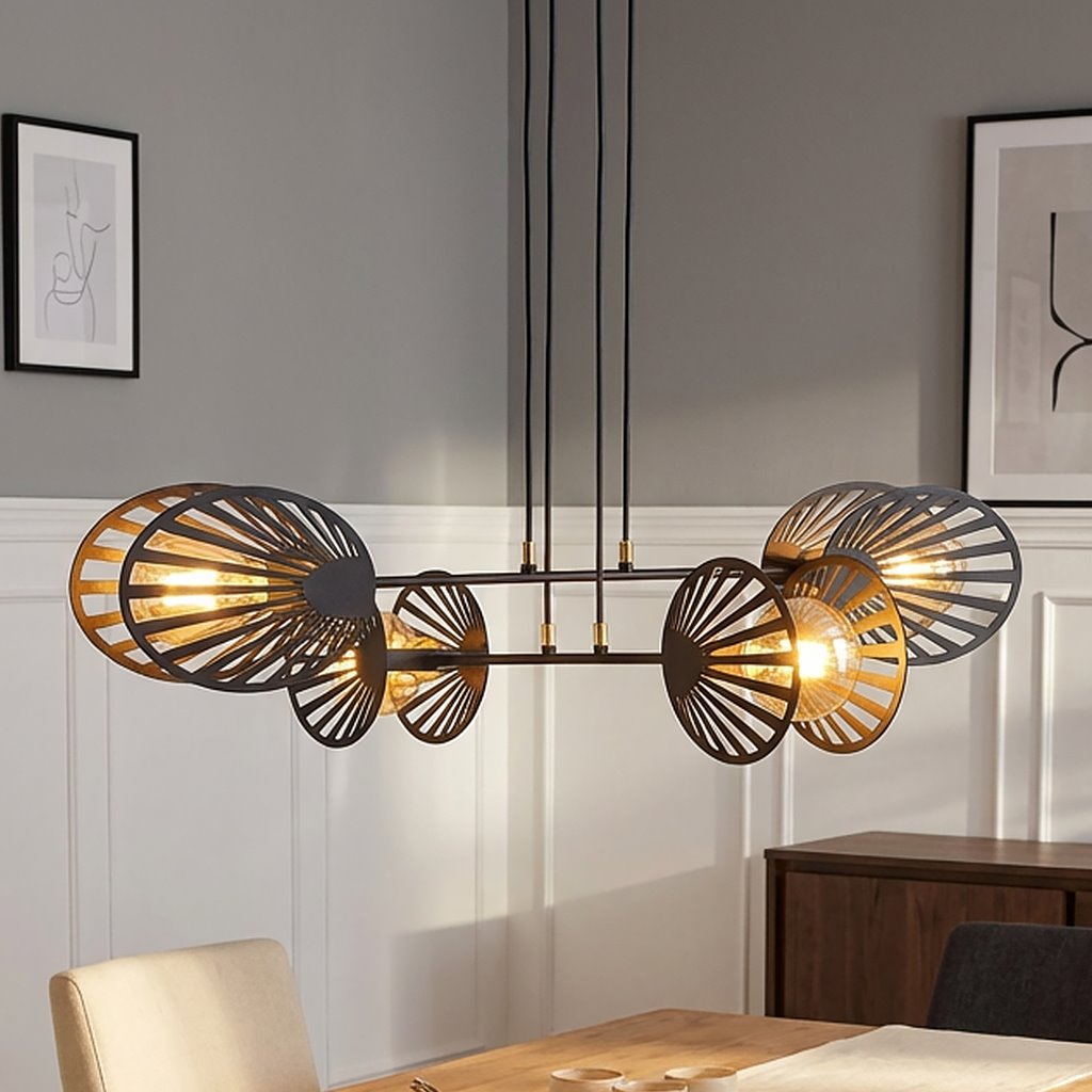 Czarna lampa wisząca Playa 4-punktowa z dekoracyjnymi, perforowanymi kloszami w kształcie liści. Zawieszona na długich, czarnych przewodach, idealna do nowoczesnych wnętrz. Tło jasnoszare, z elementami drewnianymi w aranżacji.