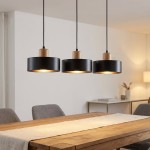 Trzy-punktowa lampa wisząca Torin w kolorze czarnym, z drewnianymi elementami, zawieszona nad drewnianym stołem. Okrągłe klosze z metalicznym wykończeniem skierowane w dół, na tle jasnej ściany. Idealna do nowoczesnych wnętrz.