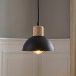 Lampa wisząca Seco z czarnym kloszem w kształcie półkuli i drewnianym uchwytem. Zawieszona na czarnym przewodzie, z widoczną żarówką E27. Tło w neutralnym kolorze, podkreślające elegancki design produktu.