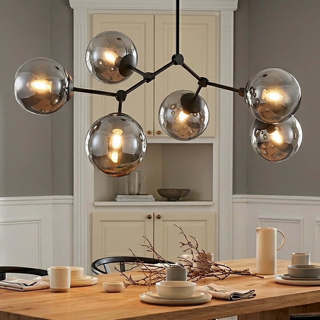 Czarna i grafitowa lampa sufitowa 6-punktowa z metalowymi kloszami w kształcie kul. Ujęcie z góry, wisząca nad drewnianym stołem, z widocznymi źródłami światła. Tło w jasnych odcieniach z meblami kuchennymi.