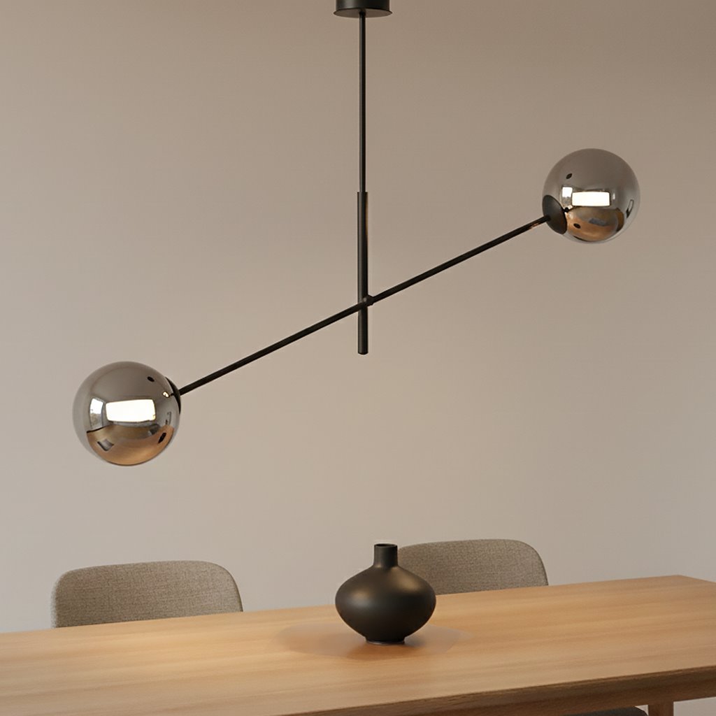 Lampa wisząca Linear 2-punktowa w kolorze czarnym i grafitowym, z dwiema metalowymi kulami na końcach poziomego ramienia. Produkt zawieszony centralnie nad drewnianym stołem, w minimalistycznym wnętrzu.