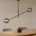 Lampa wisząca Linear 2-punktowa w kolorze czarnym i grafitowym, z dwiema metalowymi kulami na końcach poziomego ramienia. Produkt zawieszony centralnie nad drewnianym stołem, w minimalistycznym wnętrzu.