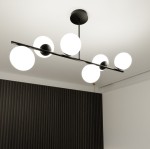 Lampa wisząca Bior 6-punktowa w kolorze czarnym, z metalową konstrukcją i sześcioma okrągłymi, białymi kloszami. Ujęcie z dołu, montowana do sufitu, w nowoczesnym wnętrzu z ciemną ścianą w tle.