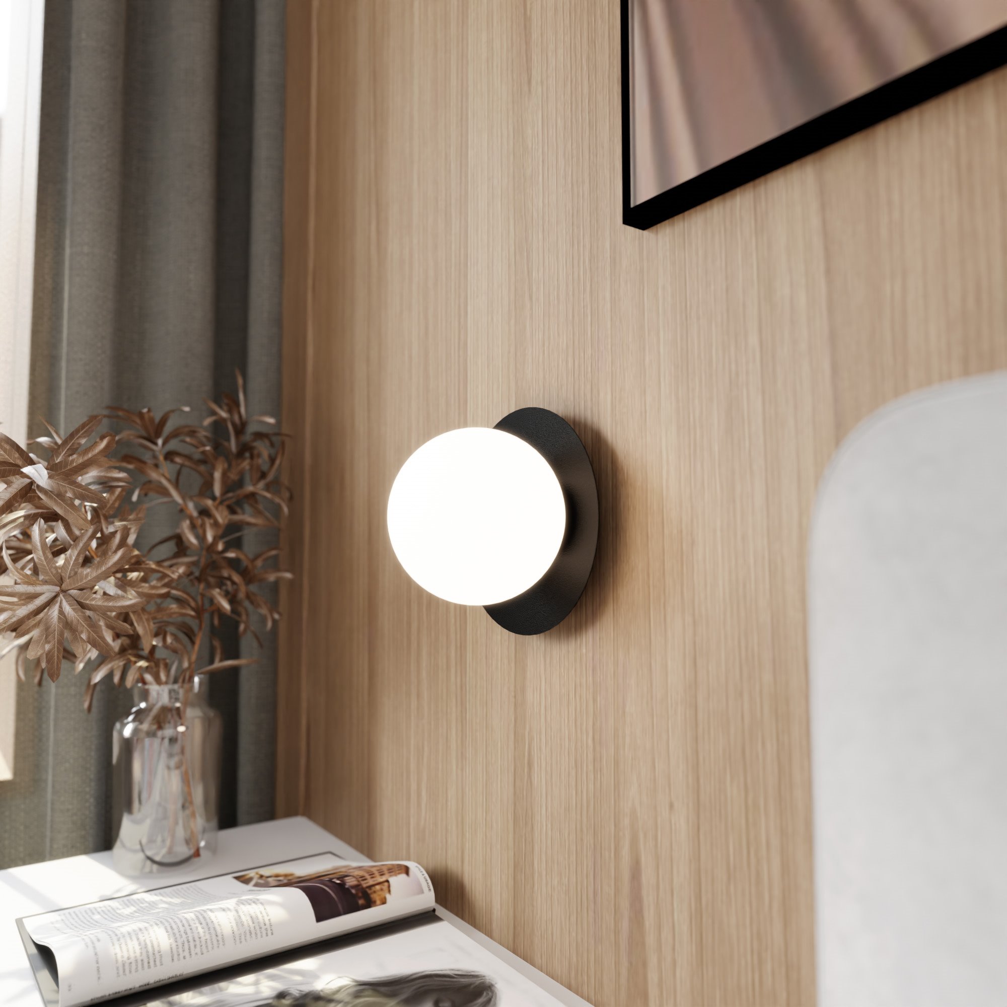 Oslo kinkiet 1-punktowy w kolorze czarnym i białym, zamontowany na ścianie. Okrągła, mlecznobiała oprawa świetlna otoczona czarnym pierścieniem. W tle drewniana ściana oraz stół z magazynem i wazonem z rośliną.