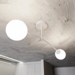 Lampa sufitowa Pregos 2-punktowa w kolorze białym, z dwoma okrągłymi kloszami, zamontowana na cienkiej, białej rurze. Ujęcie z dołu, pokazujące kształt i położenie elementów oraz sufit w tle.