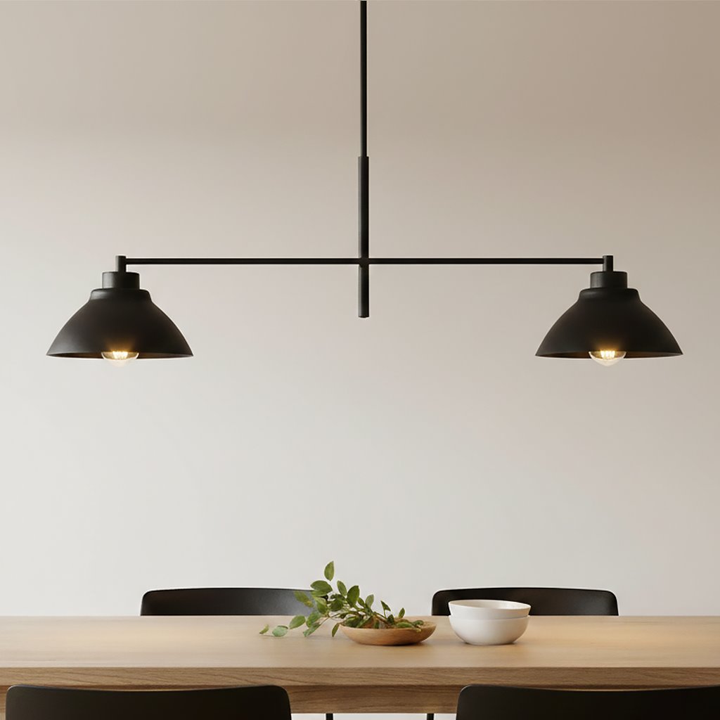 Czarna lampa wisząca Maverick 2-punktowa, z dwiema kloszami w kształcie stożka, zawieszona na cienkim stelażu. Ujęcie frontalne, produkt znajduje się nad drewnianym stołem, na którym znajdują się rośliny oraz białe naczynie. Tło jasne, minimalistyczne.