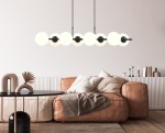 Lampa wisząca Rory 8-punktowa w kolorze czarnym z opalowymi kloszami. Zawieszona nad brązową sofą, z sześcioma okrągłymi kloszami na czarnych uchwytach. Otoczenie minimalistyczne, z okrągłym czarnym stołem i dekoracjami na białej komodzie.