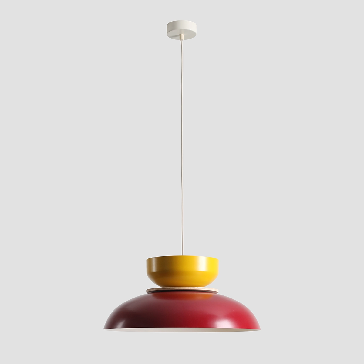 Lampa wisząca Aldo z jednym gniazdem E27 w kolorze czerwonym wina i musztardowym. Produkt zawieszony na białym przewodzie, z okrągłym, płaskim mocowaniem sufitowym. Kształt harmonijnie łączy dwa odcienie, tworząc nowoczesny akcent do wnętrza.