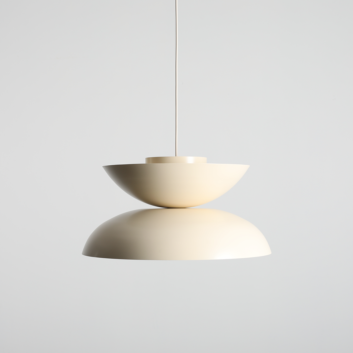 Lampa wisząca Millo w kolorze jasnej kremowej, składająca się z dwóch połączonych elementów w kształcie misek, zawieszona na cienkim przewodzie. Produkt wykonany z matowego materiału, z widocznym gwintem E27.
