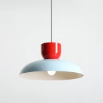 Lampa wisząca Ella z kloszem w kolorze błękitnym i czerwonym uchwytem. Wisi na czarnym przewodzie, z widoczną żarówką E27. Kształt okrągły, z matowym wykończeniem. Tło proste, jasne.