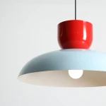 Lampa wisząca Ella z jedną oprawą E27 w kolorze ciemnego błękitu i czerwonej papryki. Posiada zaokrąglony klosz oraz okrągłą, błyszczącą podstawę. Zawieszona na czarnym kablu, idealna do nowoczesnych wnętrz.