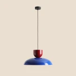 Lampa wisząca Ella z kloszem w kolorze ciemnego kobaltu i czerwonym elementem u góry. Zawieszona na czarnym przewodzie, z okrągłym mocowaniem sufitowym. Prosty, nowoczesny design, idealna do wnętrz.