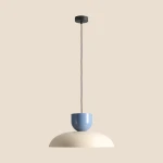 Lampa wisząca Ella z jedną oprawą E27 w kolorze ciemnej kremowej z kloszem w odcieniu przybrudzonego błękitu. Produkt zawieszony na czarnym kablu, prezentujący minimalistyczny design.