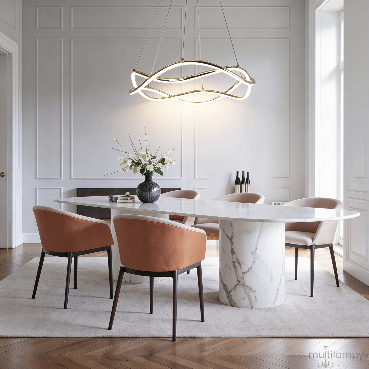 Lampa wisząca LED 36W CCT w kolorze złotym, o nowoczesnym, falistym kształcie, zawieszona nad okrągłym stołem w eleganckim wnętrzu. W tle widoczne są krzesła z tapicerowanymi siedzeniami w kolorze brązowym i dekoracyjny wazon z kwiatami.