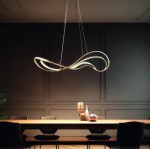 Lampa wisząca LED Twist 60W w kolorze złotym o nowoczesnym, falistym kształcie, zawieszona nad drewnianym stołem w eleganckim wnętrzu. Tło w ciemnym odcieniu podkreśla jej stylowy design.