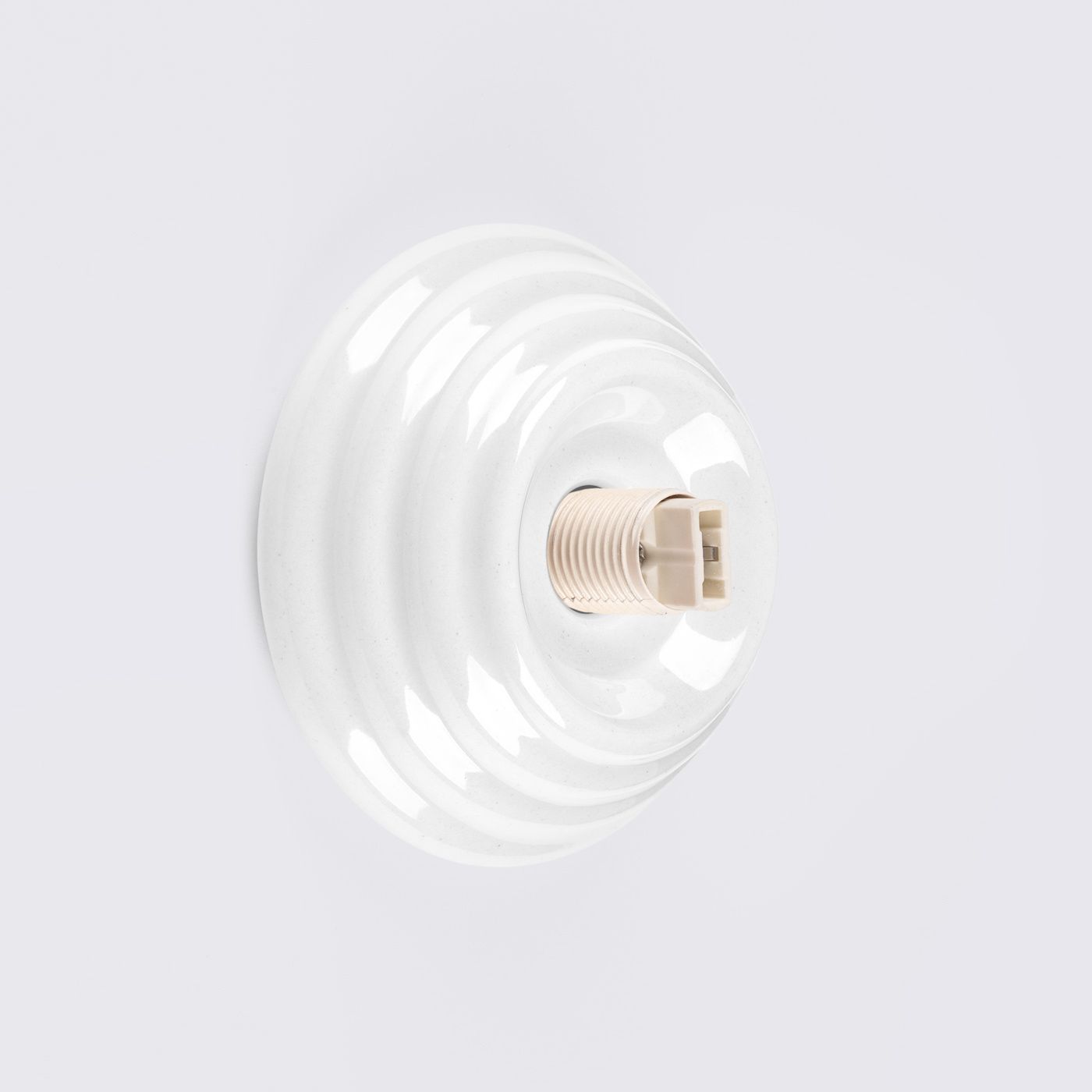 Biały kinkiet Zori z oprawą na żarówkę G9, z powierzchnią o lekkiej teksturze, w kształcie okrągłej, falistej tarczy. Produkt montowany na ścianie, z podświetlonym gniazdem, przeznaczony do użytku zewnętrznego (IP44).