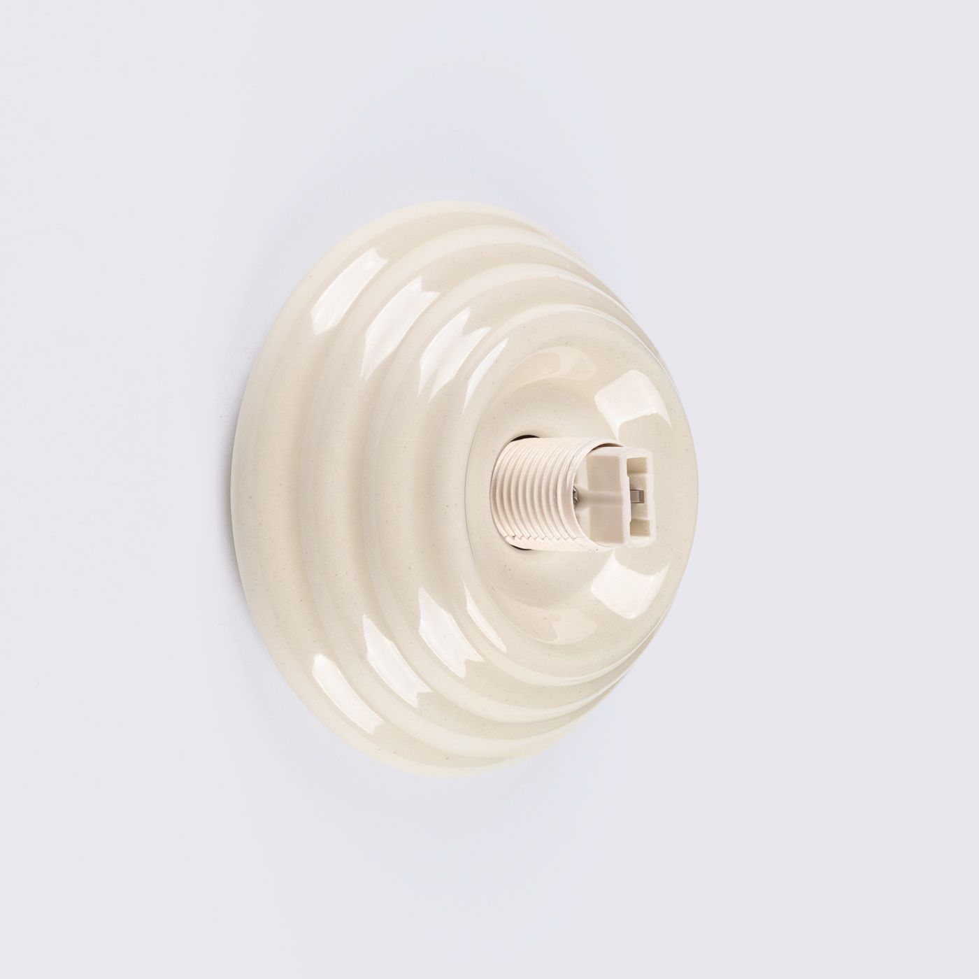 Kinkiet Zori 1xG9 IP44 w kolorze beżowym, o okrągłej, gładkiej podstawie z delikatnymi wzorami. Widoczny gwint do żarówki G9. Produkt umieszczony na jasnym tle, ukazany z góry.