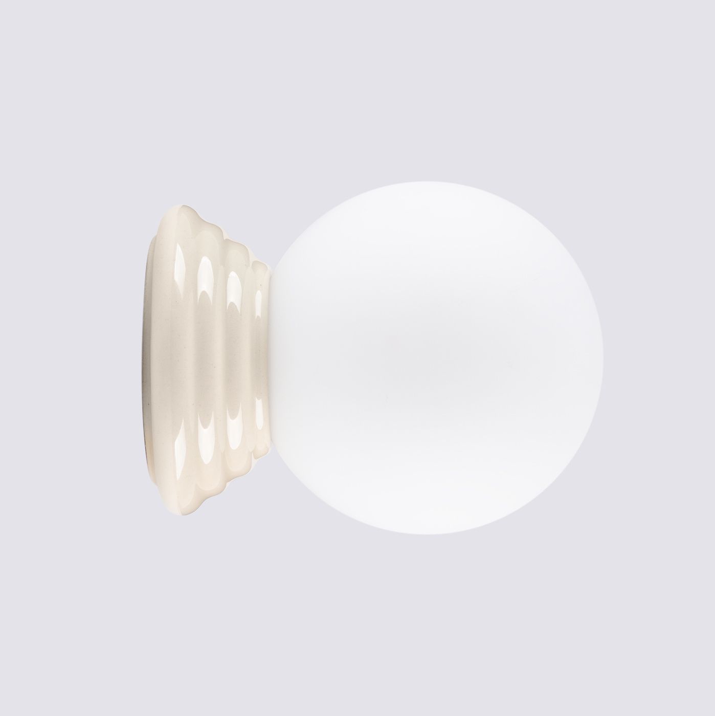 Kinkiet Zori 1xG9 IP44 w kolorze beżowym z okrągłą, matową kloszem. Ujęcie frontalne, produkt stojący na dekoracyjnej, falistej podstawie. Biały klosz kontrastuje z beżową bazą, tworząc elegancki wygląd.